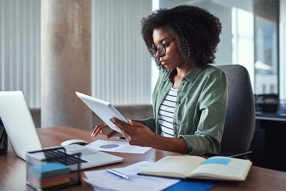 How To Start a Home Business: A woman sitting at a desk with a laptop and some paperwork.