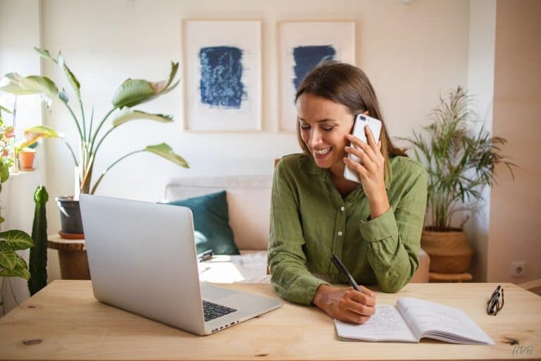 woman at desk on cell phone with laptop