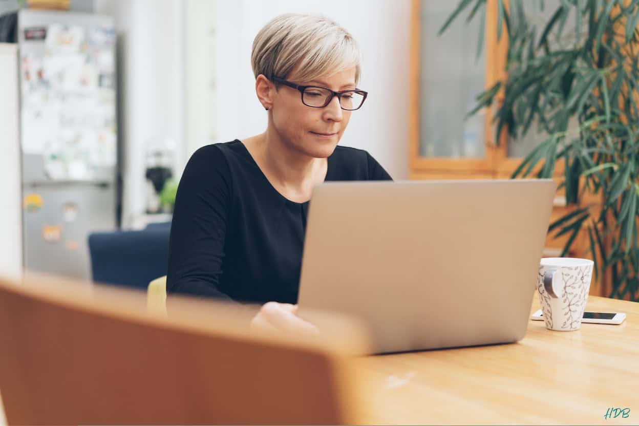 Midlife woman sitting at table with laptop.